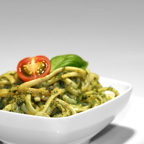 Nudeln mit Basilikumpesto und Tomate in einer weißen Schüssel,